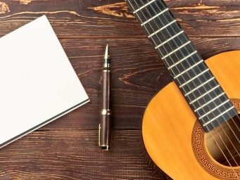 A guitar, pen, and writing pad.